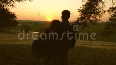 女孩和男人旅行，在森林里散步，在日落时欣赏风景。 情侣旅行者带着背包旅行。 幸福家庭